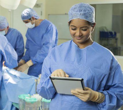 Female clinician in scrubs looking at a tablet